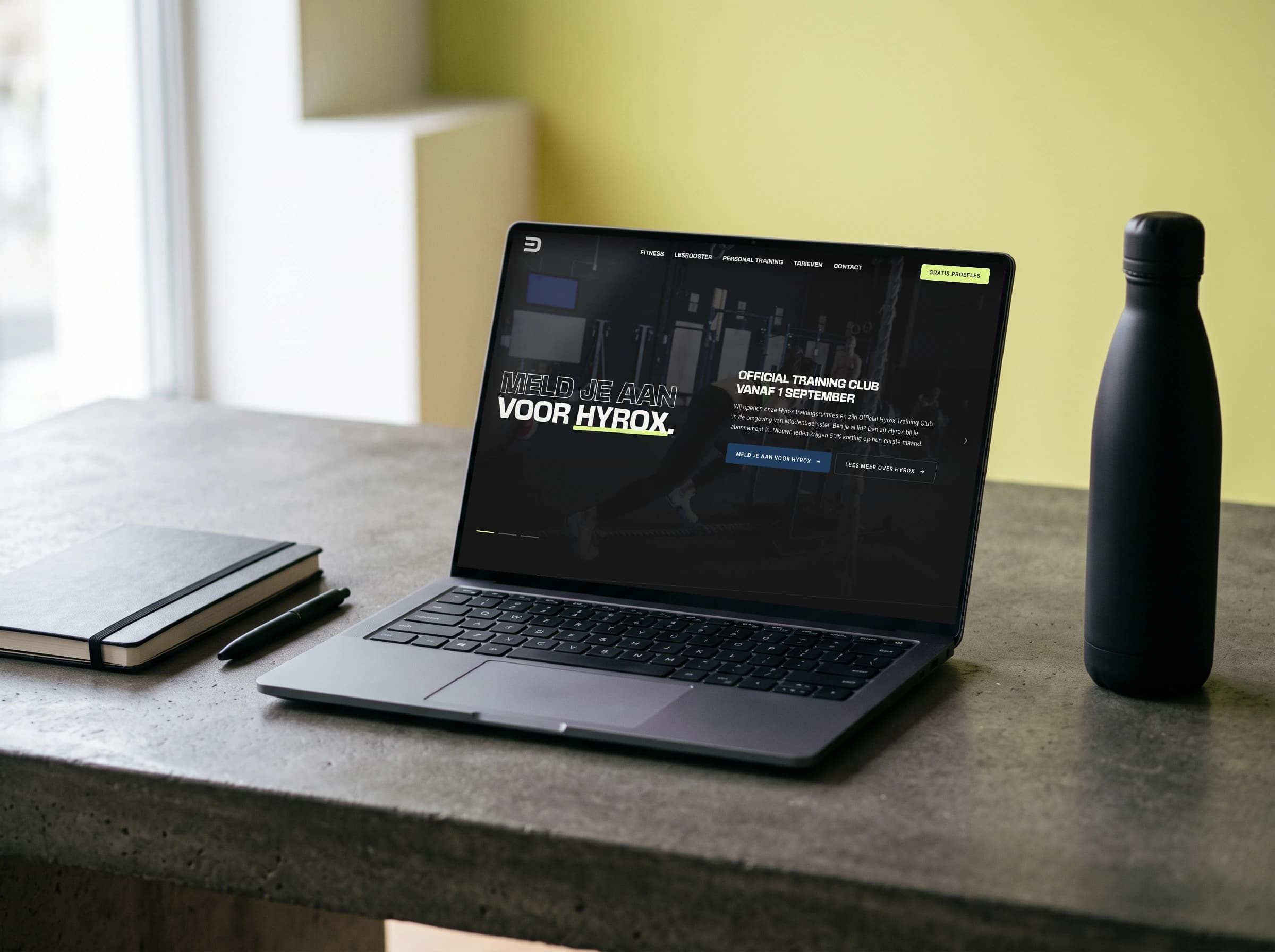 De homepage van De Kloek Fitness op een laptop op een betonnen bureau